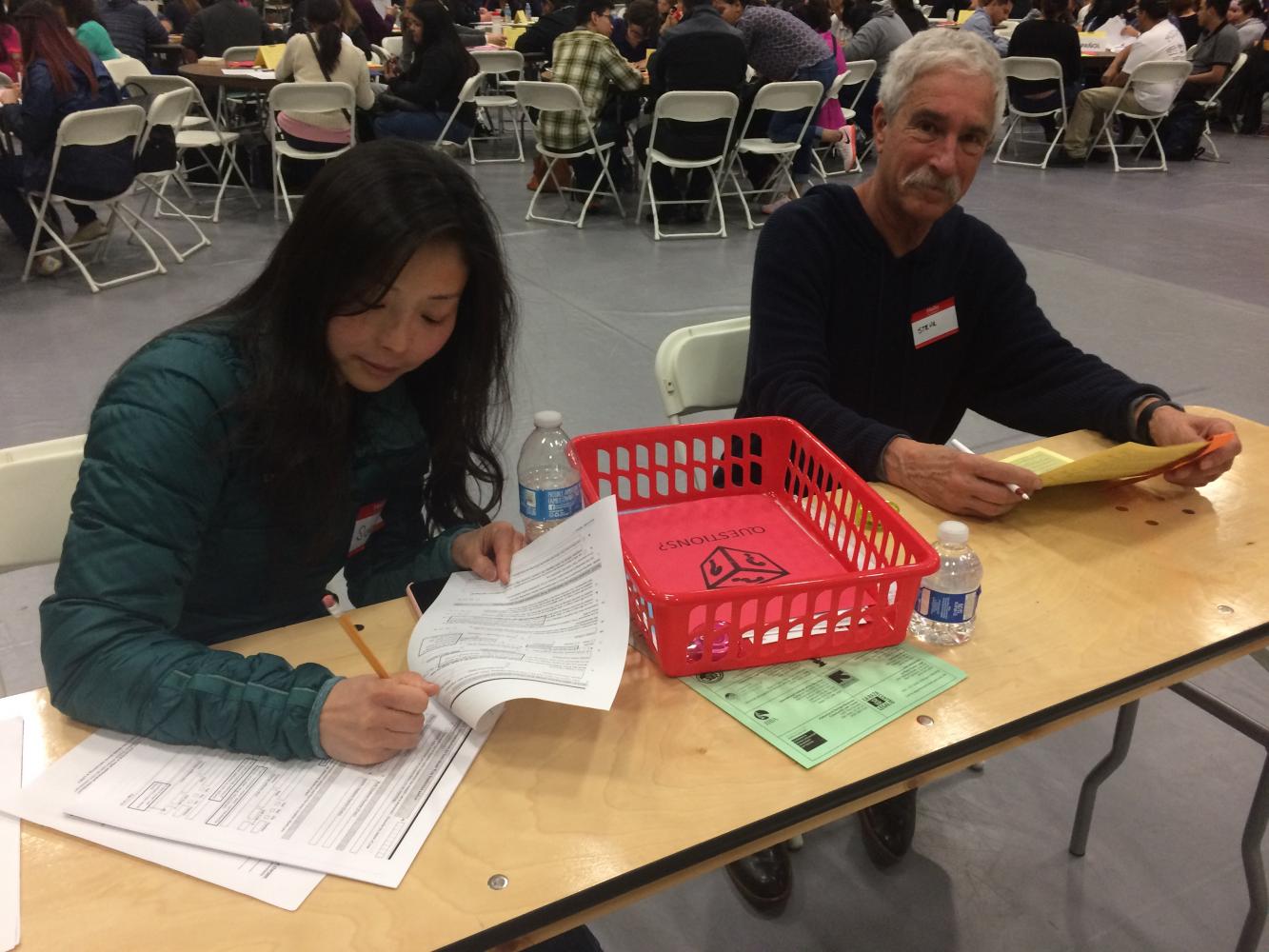 Immigration Workshop volunteers (left) Susan Jang and Steve Ravel help attendees fill out citizenship applications in the SJCC gym, Saturday April 22.