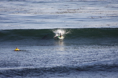 The surfer is driving hard with kicking in the water and paddling. 