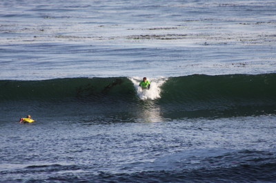 The surfer’s arms are extended supporting his upper weight.