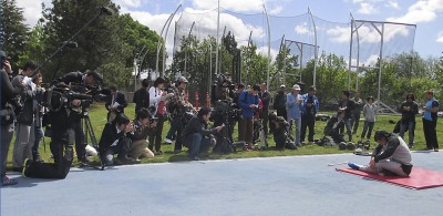 Members of the media gather around Olympic athlete Koji Murofushi as he performs warm-up stretches prior to beginning his weekly training routine.  Murofushi will compete in the hammer throw competition at the 2012 London Olympics.