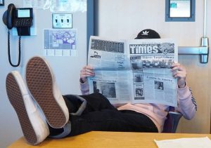 City College Times Editor-in-Chief Jasper Somera relaxes in the newsroom with a copy of the City College Times newspaper.