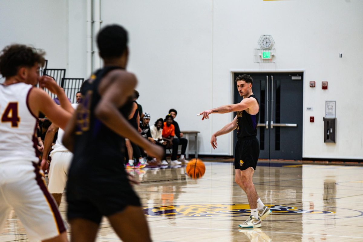 Jaguars’ point guard Matt McAndrews dribbling the ball up the floor while communicating a playcall to the rest of his teammates.