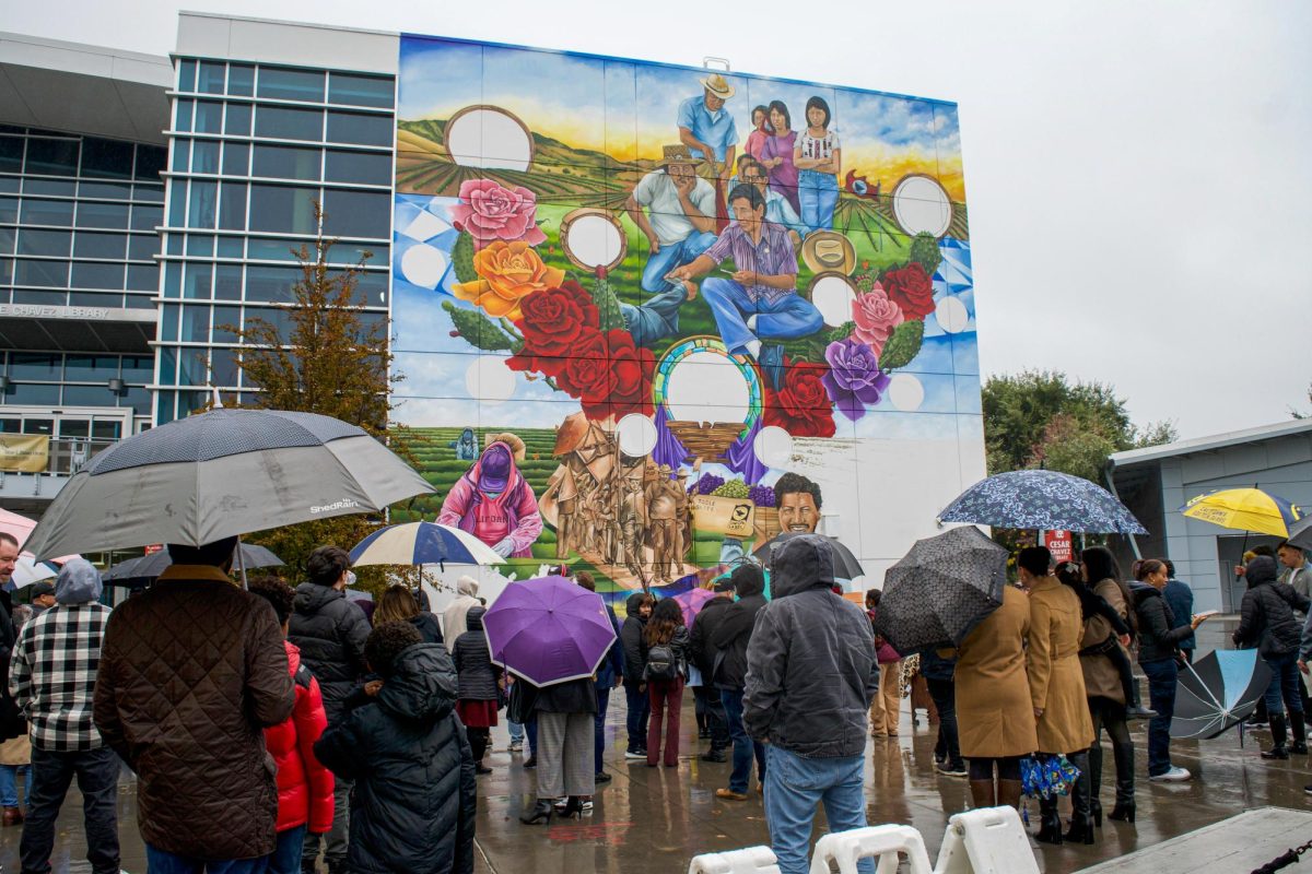 Students, faculty and members of the Chávez family gathered around the César Chávez Mural, braving the rain beneath umbrellas and jackets, awaiting the Nov. 25 ribbon-cutting ceremony. 